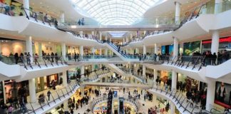 Alışveriş merkezleri, modern şehir yaşamının vazgeçilmez ticaret ve sosyal yaşam alanları arasında yer alırken, beraberinde getirdiği trafik ve ulaşım sorunları da şehir planlamasının en önemli gündemlerinden biri olmaya devam ediyor. AVM Trafik ve Ulaşım Sorunları, özellikle büyükşehirlerde artan araç sayısı, yoğun ziyaretçi trafiği ve toplu taşıma kapasitesiyle birlikte daha fazla önem kazanan konular arasında bulunuyor. Alışveriş merkezlerinin bulunduğu bölgelerde oluşan yoğunluk, yalnızca ziyaretçileri değil çevrede yaşayan vatandaşları ve şehir içi ulaşımı da doğrudan etkiliyor. Konulu bir haber görseli.
