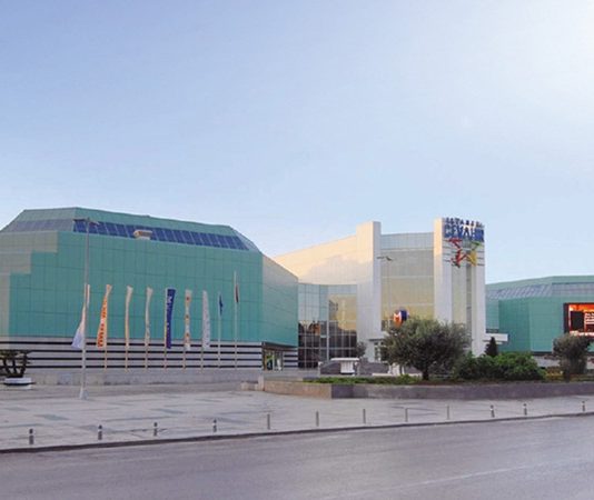 AVM’lerin Şehir Ekonomisine Katkısı Modern şehirlerin ekonomik yapısında önemli bir yere sahip olan alışveriş merkezleri, yalnızca ticari faaliyetlerin yürütüldüğü alanlar olmaktan çıkarak istihdam, yatırım ve sosyal yaşam açısından da büyük değer üreten merkezlere dönüştü. Günümüzde AVM yatırımları, şehir ekonomilerinin büyümesine katkı sağlayan en önemli unsurlardan biri olarak değerlendiriliyor. Perakende sektörünün gelişmesine destek veren alışveriş merkezleri, farklı sektörlerle kurduğu güçlü bağ sayesinde ekonomik hareketliliğin artmasına önemli katkılar sunuyor. Konulu bir haber görseli.